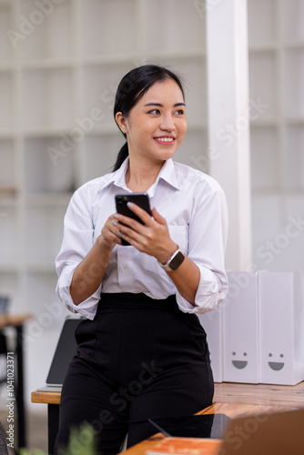 Asian women hold smartphone and use pc at the workplace. Project stats financial data sales charts on laptop and cellphone 