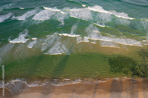 Aerial views of waves from the sea crashing against the beach in Fingal Head, New South Wales, Australia photo