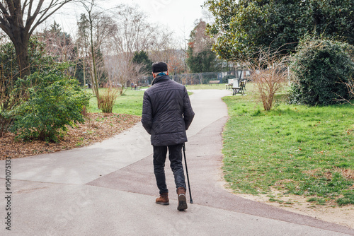 Personne âgée marchant avec un canne. Homme âgé en promenade dans un parc. Vieil homme marchant péniblement. Retraité en balade photo