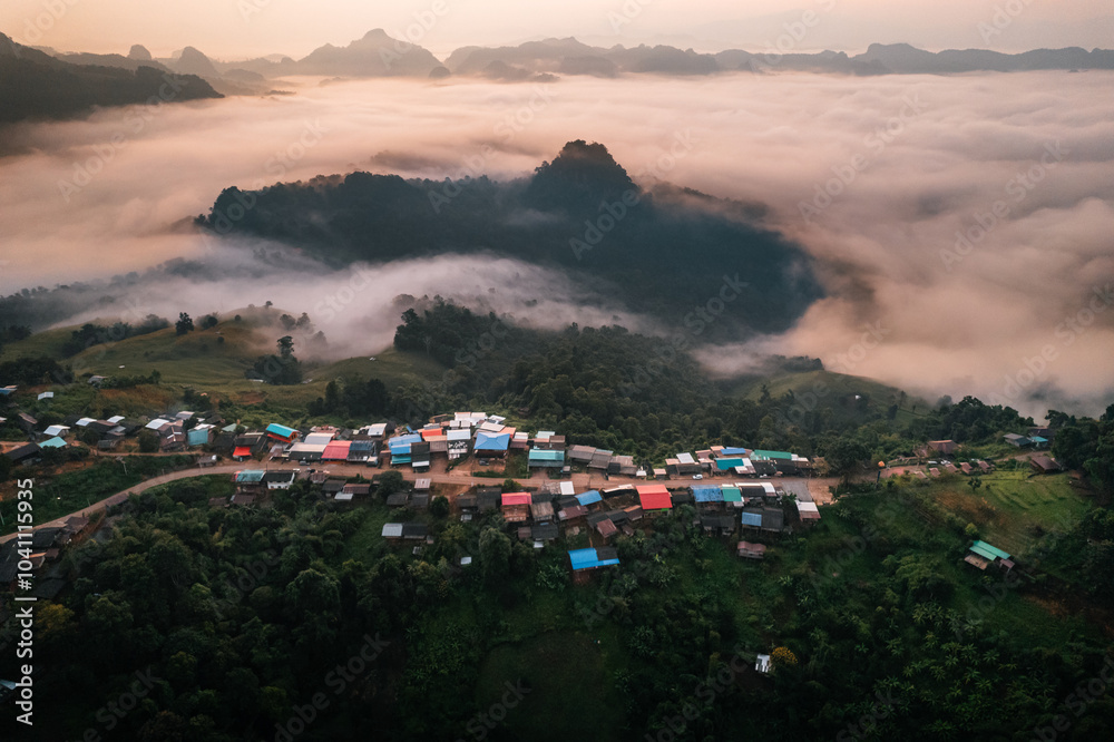 Fototapeta premium Aerial view of Morning fog and mountains with a rural village and sunrise from above