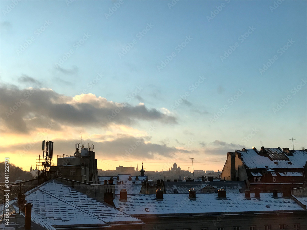 Photo panorama of the old city. Winter, snowy roofs. Sunset or sunrise. The sky of different shades. Blue, yellow, pink. Clouds. Blurry distant plan. Photo panorama of the old city. Winter, snowy roofs. Sunset or sunrise. The sky of different shades. Blue, yellow, pink. Clouds. Blurry distant plan.