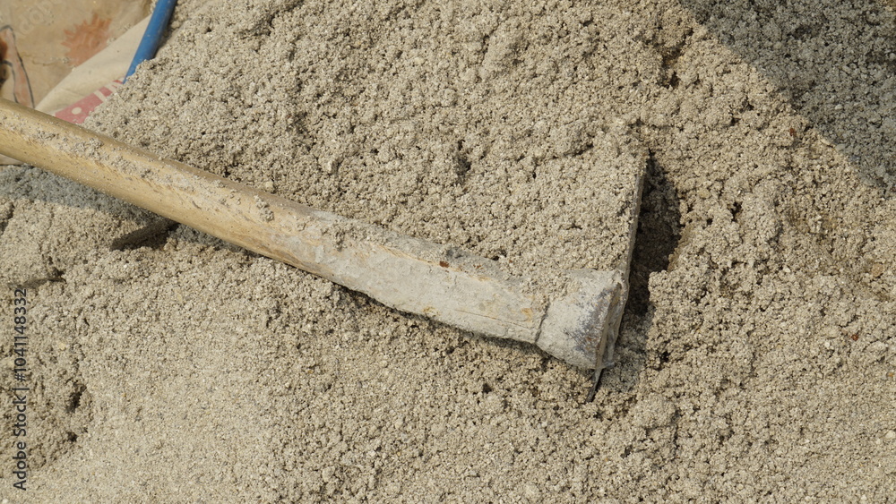 A hoe located on the sand that builders usually use to stir building materials
A hoe located on the sand that builders usually use to stir building materials