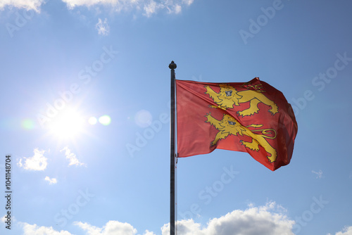Flag of Normandy, two yellow lions on a red background, fluttering on a sunny sky.