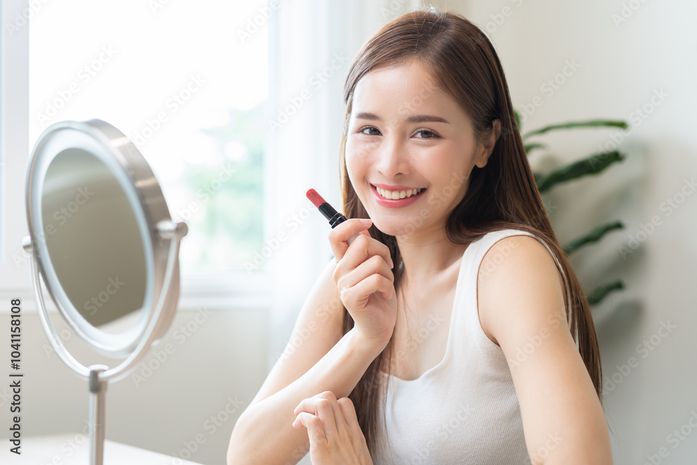 Skin care, beauty cosmetics concept, pretty asian young woman, girl make up face by applying red lipstick, lips balm on her mouth, looking at the mirror at home. Female look with natural fashion style Skin care, beauty cosmetics concept, pretty asian young woman, girl make up face by applying red lipstick, lips balm on her mouth, looking at the mirror at home. Female look with natural fashion style