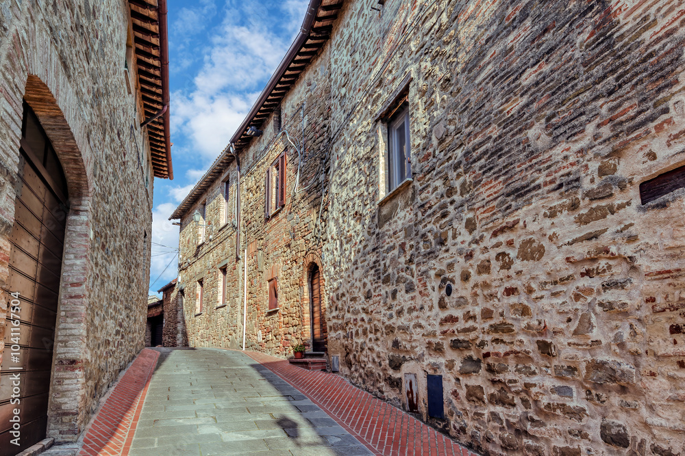 The narrow alleyways of Collemancio reveal beautifully preserved medieval architecture set against the backdrop of a clear blue sky in Umbria. Village Collemancio - Italian national heritage