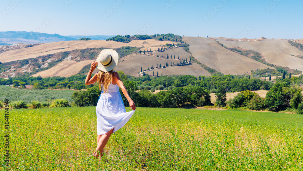 Obraz premium Young female wearing a white dress relaxing in green field in Tuscany, Italy