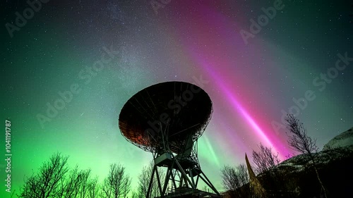 Northern lights in sky with stars above parabolic research antenna, time lapse photo