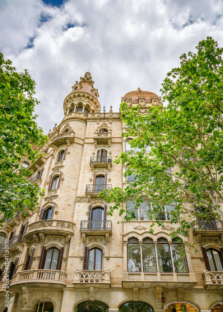 Naklejka premium Ornate building in Barcelona with arched windows, decorative balconies, and elaborate stone carvings. A blend of Gothic and Renaissance elements.