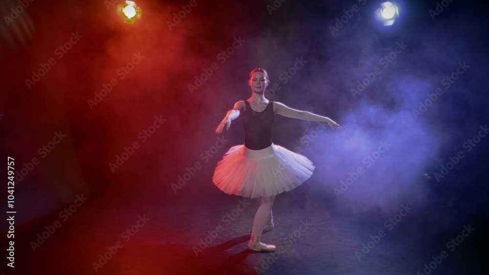 Talented ballerina performing fouettes and classical ballet steps in studio. Full-length portrait of beautiful graceful lady in tutu dancing alone in rehearsal room with red and blue light of soffits Talented ballerina performing fouettes and classical ballet steps in studio. Full-length portrait of beautiful graceful lady in tutu dancing alone in rehearsal room with red and blue light of soffits