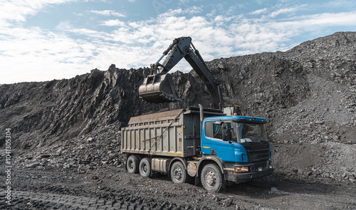 Large quarry dump truck and excavator. Big mining truck work coal deposit. Loading coal into body truck. Production useful minerals. Mining mining machinery to transport coal from open-pit production photo