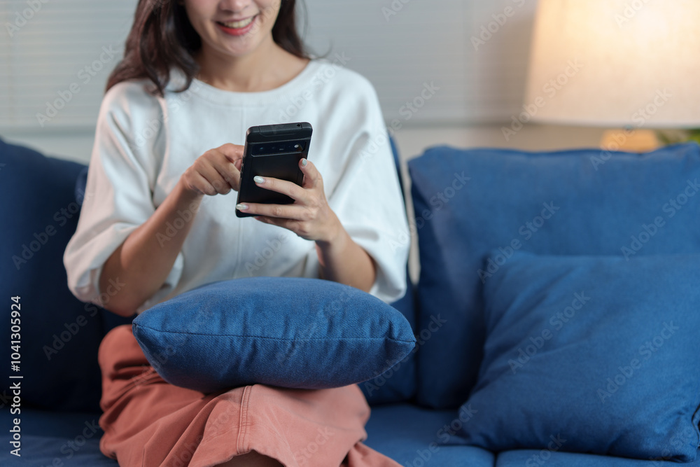 Cheerful Asian woman using mobile phone Chat on the website, application, download, work or study online. Sit on the sofa and relax. modern technology concept Cheerful Asian woman using mobile phone Chat on the website, application, download, work or study online. Sit on the sofa and relax. modern technology concept