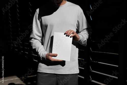 Man holding a blank book mockup template in an urban outdoor environment with sharp sunlit shadows. Isolated surface to place your design.  photo