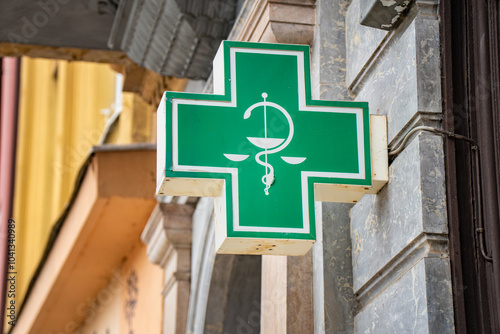 Informative green pharmacy sign featuring caduceus symbol in urban setting of Czechia