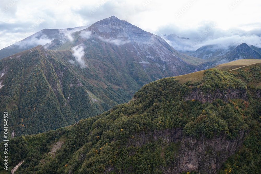 Expansive mountain landscape view with lush valleys, gentle clouds, and distant peaks captured during daylight in a remote location Expansive mountain landscape view with lush valleys, gentle clouds, and distant peaks captured during daylight in a remote location