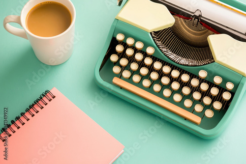 Vintage typewriter, notebook, and coffee on a pastel-colored surface.