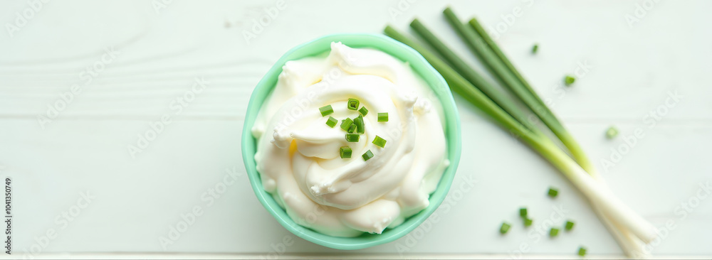Sour cream in bowl with onion chives on top of wooden table. Top view. Sour cream in bowl with onion chives on top of wooden table. Top view.