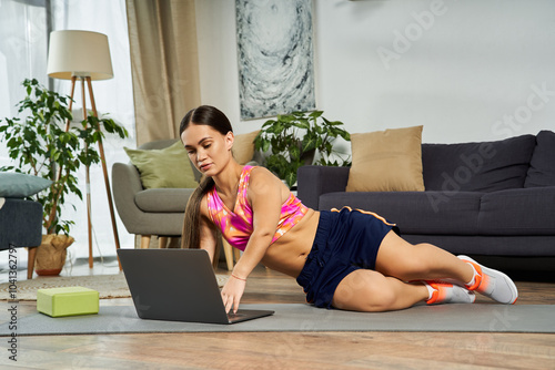 With dedication, a short-statured brunette woman engages in online fitness, making the most of her at-home workout session. photo