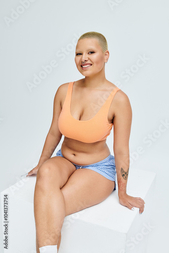 A young bald woman exudes confidence in colorful clothing while posing gracefully. photo