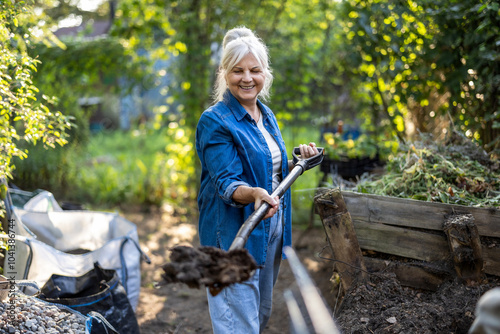 Canvas Print Senior woman shoveling compost heap in her garden