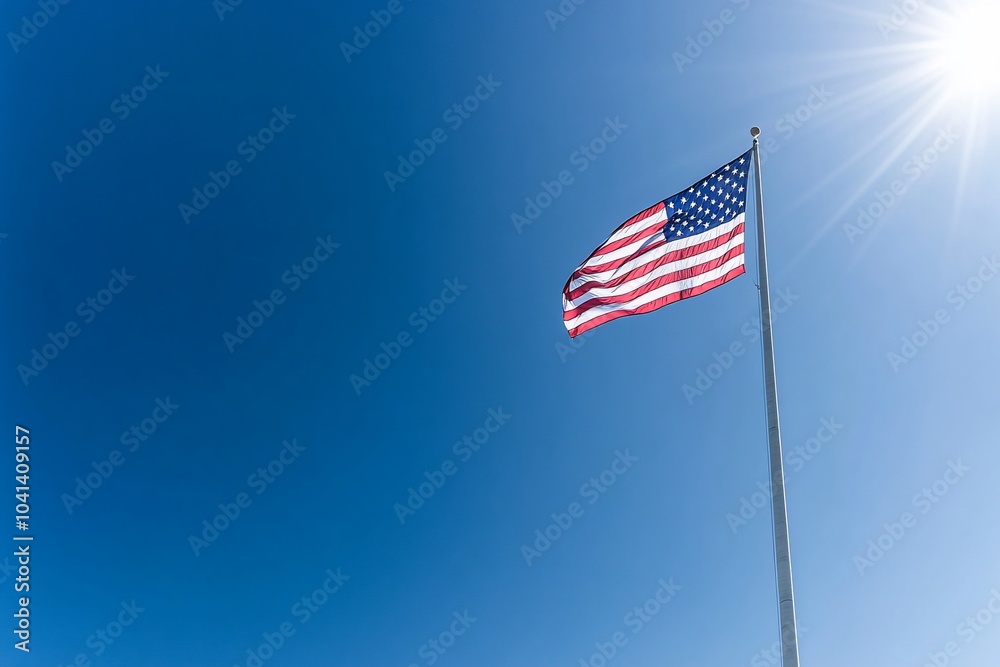 The American flag waves proudly against a bright blue sky with the sun shining. The American flag waves proudly against a bright blue sky with the sun shining.