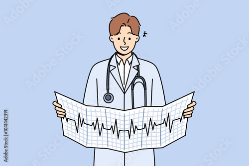 Man cardiologist holds result of ecg analysis and smiles, standing in white coat with stethoscope around neck. Cardiologist looks for symptoms of disease by observing rhythm of patient heartbeat