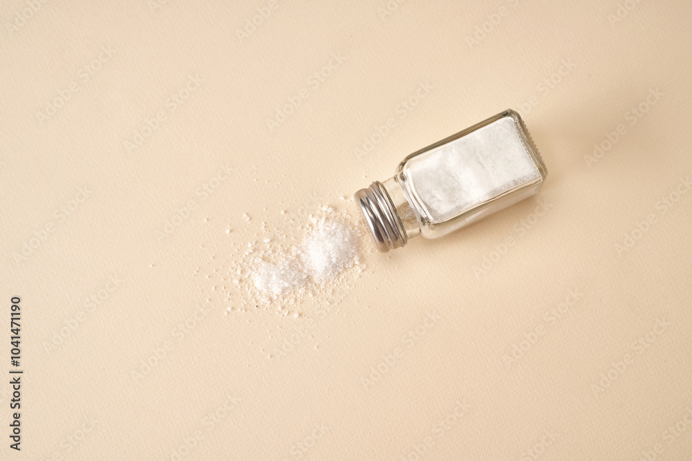 Salt shaker on beige background. Heap of sea salt on the table. Salt shaker on beige background. Heap of sea salt on the table.