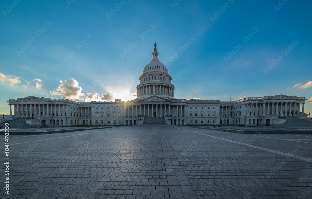 United States Capitol with a shining sun on the background at sunset