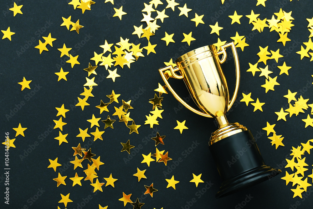 Golden trophy cup with confetti on black background