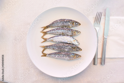 Top view of five roasted sardines on a white plate photo