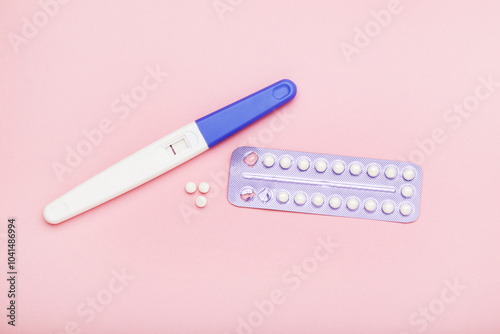 Oral contraceptive pills and pregnancy test on pink background