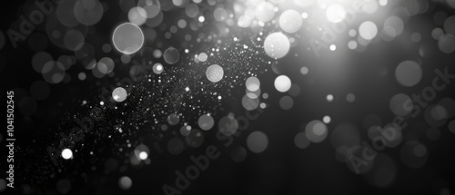 Abstract black and white background featuring shimmering bokeh circles and glittering silver particles, creating an elegant, sparkling visual effect