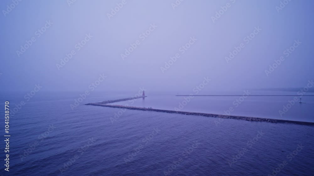 Drone shot flying away from lighthouse on the end of a breakwater in lake Michigan Drone shot flying away from lighthouse on the end of a breakwater in lake Michigan