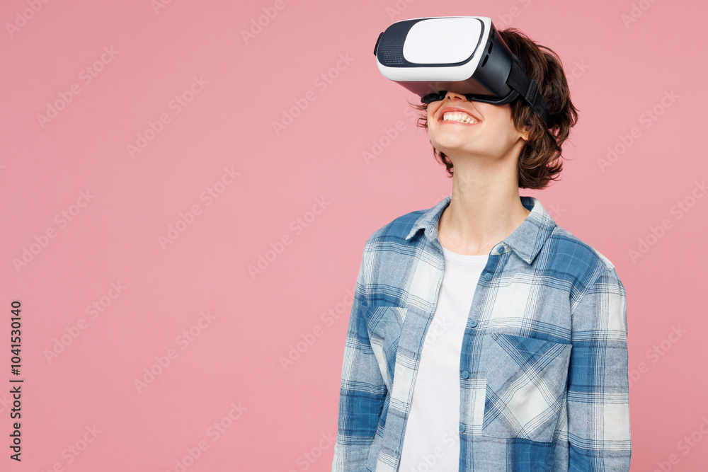 Young smiling woman she wear blue shirt white t-shirt casual clothes watching in vr headset pc gadget look overhead isolated on plain pastel light pink background studio portrait. Lifestyle concept. Young smiling woman she wear blue shirt white t-shirt casual clothes watching in vr headset pc gadget look overhead isolated on plain pastel light pink background studio portrait. Lifestyle concept.