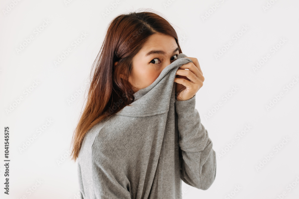 Asian Thai woman holding sweater, hiding and covering her face, shy and embarrassing, smelly standing isolated over white background wall. Asian Thai woman holding sweater, hiding and covering her face, shy and embarrassing, smelly standing isolated over white background wall.