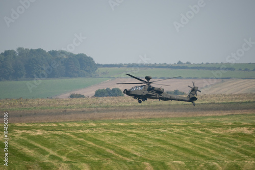 British army Boeing Apache Attack helicopter gunship AH64E AH-64E ArmyAirCorp hovering at low level over a grass meadow