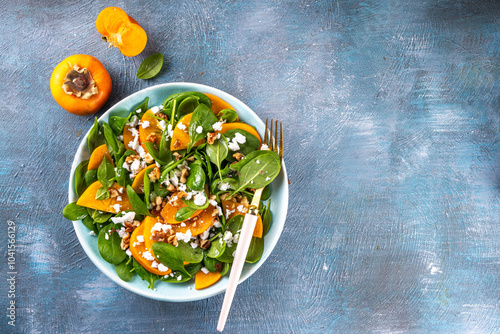 Sweet, savory delicious Persimmon autumn Salad with baby spinach leaves, cottage cheese and walnuts, with apple cider dressing, olive oil and honey photo