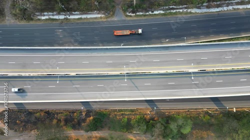 Top-down aerial view of a multilane highway with cars and trucks moving in opposite directions, highlighting modern road infrastructure.
