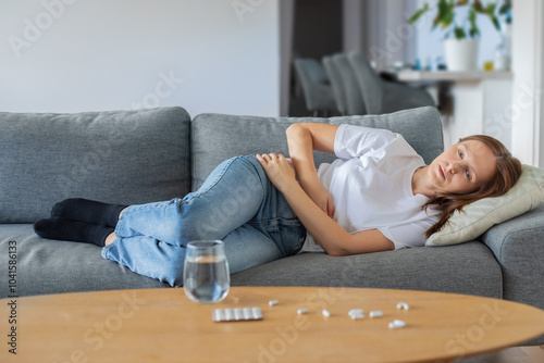 Принти на полотні Young woman lying on sofa and suffering from abdominal pain at home