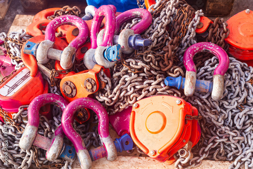 Fotografía Industrial chain hoists with steel shackles lie in a pile.
