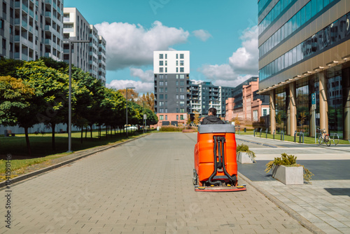 Street cleaner, road sweeper cleaning on the floor in city of Krakow, Poland. Cityscape of a residential area with modern apartment buildings, new green urban landscape in the city. High quality photo photo