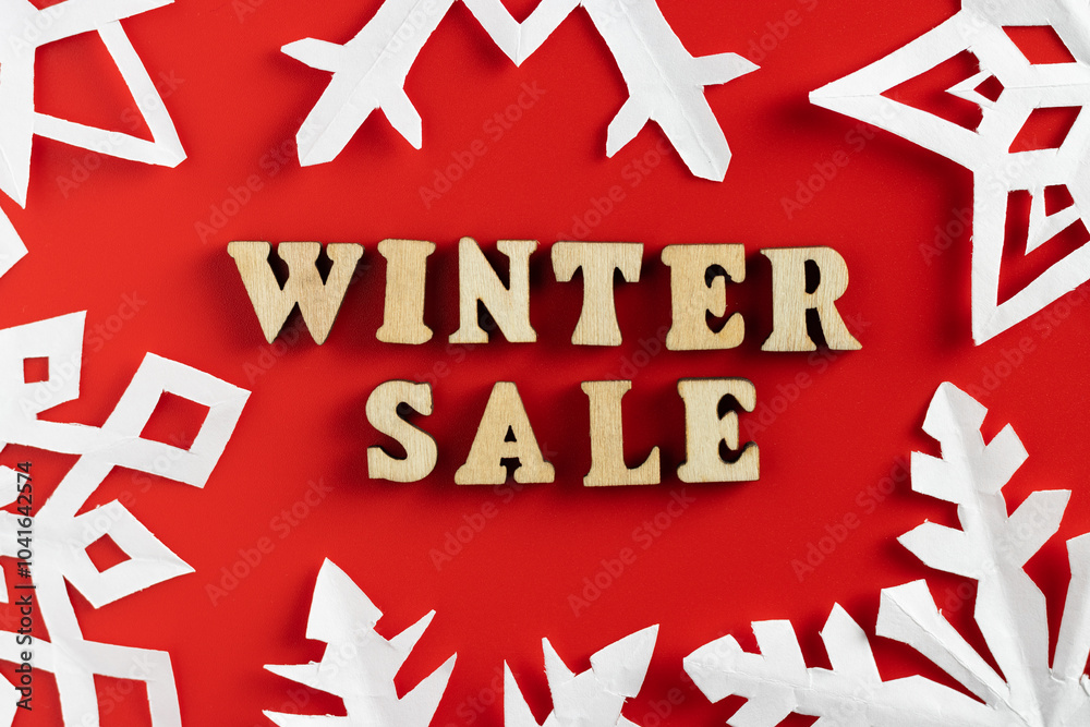 winter sale wording with paper cut out snowflakes on red background. selective focus winter sale wording with paper cut out snowflakes on red background. selective focus