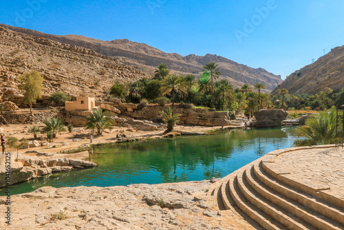 Exploring the stunning Wadi Shab Oasis in Oman with its refreshing waters and lush palm trees under clear blue skies