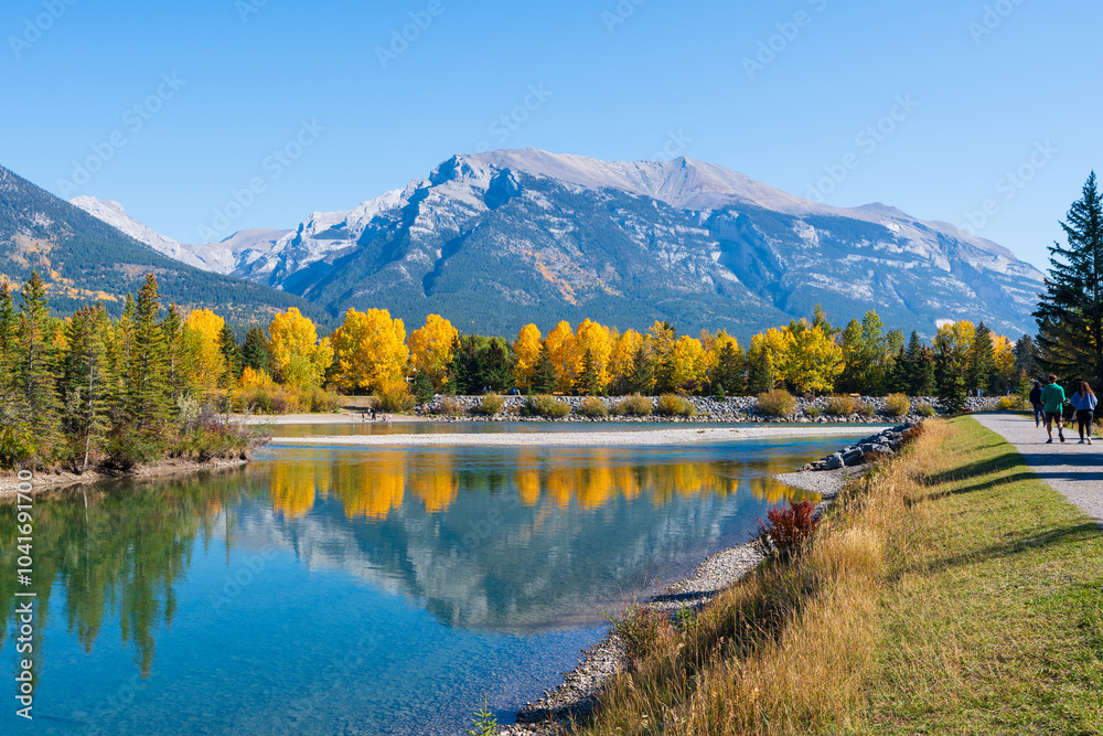 Obraz premium People are walking along the Bow River riverside trail in autumn. Canmore, Alberta, Canada. Rundle Plante Lane.