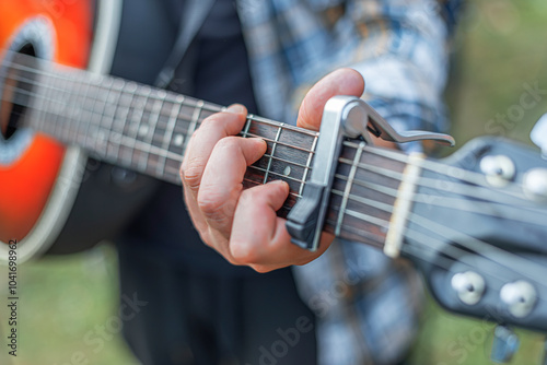 Male hands with an acoustic guitar against a background of a country landscape.