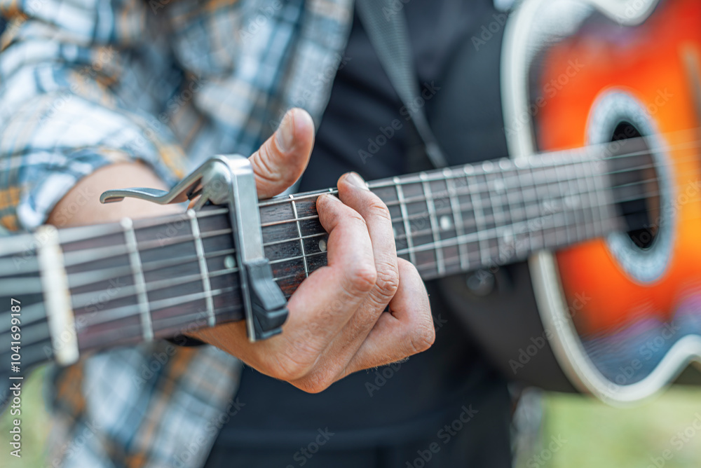 Male hands with an acoustic guitar against a background of a country landscape.