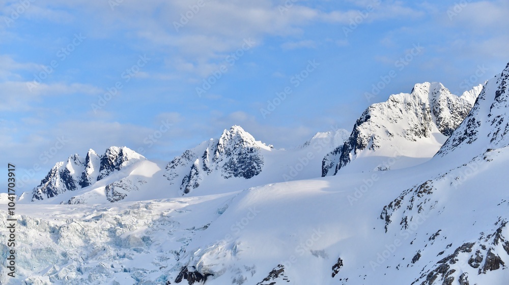 Fototapeta premium Mountain peaks and snow in The Arctic, against a blue sky.