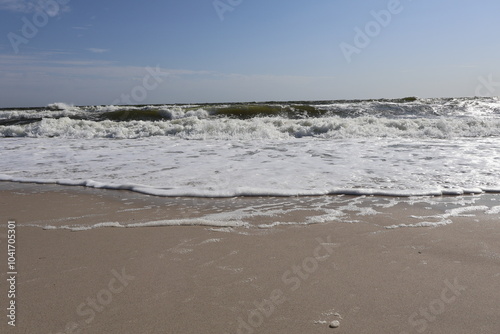 Ocean Waves Rolling onto Sandy Beach under Clear Sky