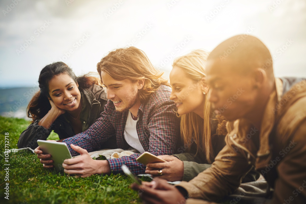 Fototapeta premium Happy, students and friends in park on tablet for online learning, social media and internet outdoors. Diversity, relax and men and women on digital tech for education, studying and college in nature