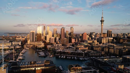 Auckland, New Zealand: Cinematic aerial drone footage of the sun sets over the Auckland business district skyline in New Zealand largest city. Shot with a forward and rotation motion.