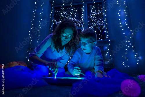 Child and therapist in sensory stimulating room, black snoezelen. Autistic child playing with therapist during occupational therapy session. photo